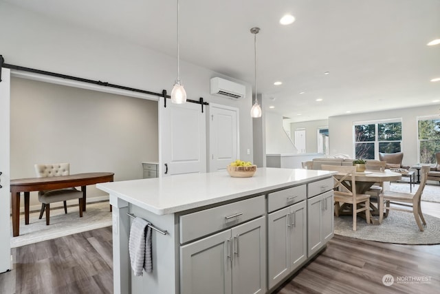 kitchen featuring hanging light fixtures, a barn door, dark hardwood / wood-style floors, and a wall unit AC