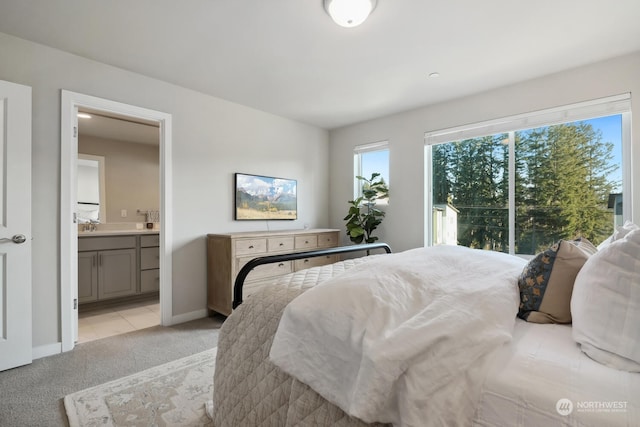 bedroom featuring connected bathroom, sink, and light colored carpet