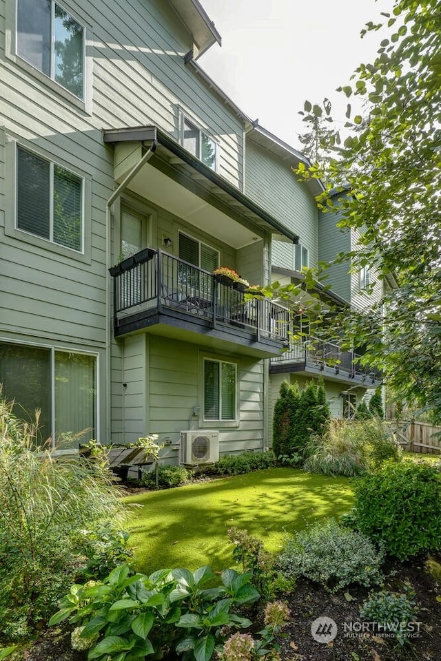 back of property featuring ac unit and a lawn