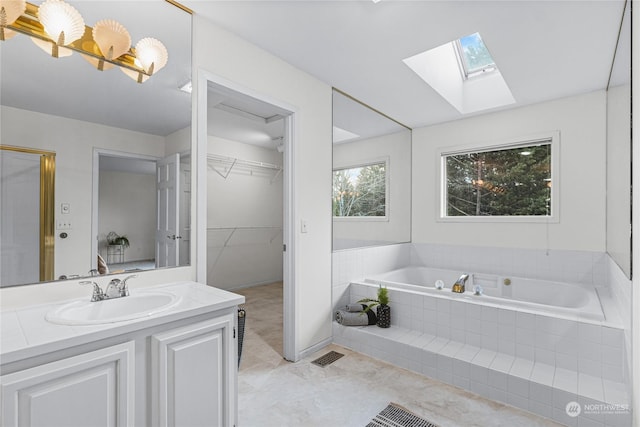 bathroom with vanity, tiled bath, and a skylight