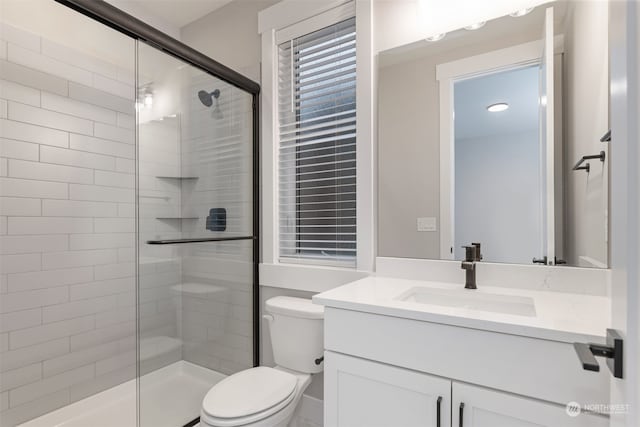 bathroom featuring vanity, a shower with shower door, and toilet