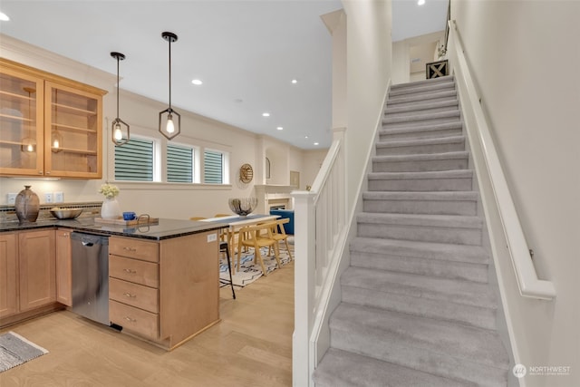 kitchen featuring pendant lighting, dishwasher, a kitchen bar, dark stone counters, and light hardwood / wood-style floors