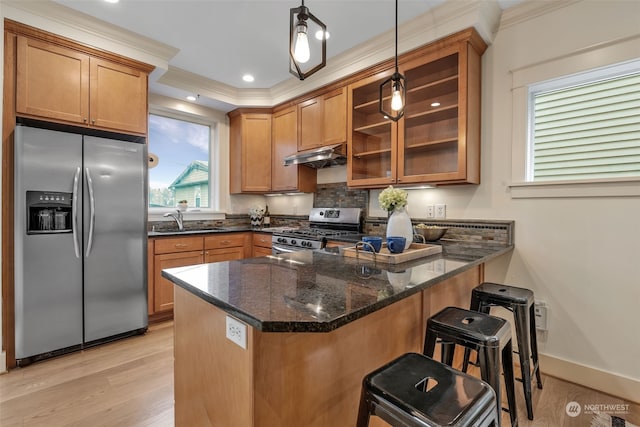 kitchen with a breakfast bar, hanging light fixtures, appliances with stainless steel finishes, kitchen peninsula, and dark stone counters