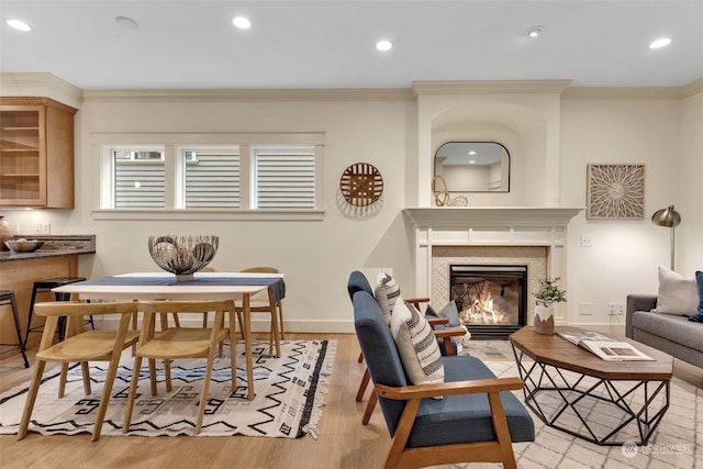 living room featuring ornamental molding, a fireplace, and light hardwood / wood-style floors