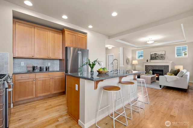 kitchen with light wood-style flooring, a fireplace, stainless steel appliances, and a kitchen breakfast bar