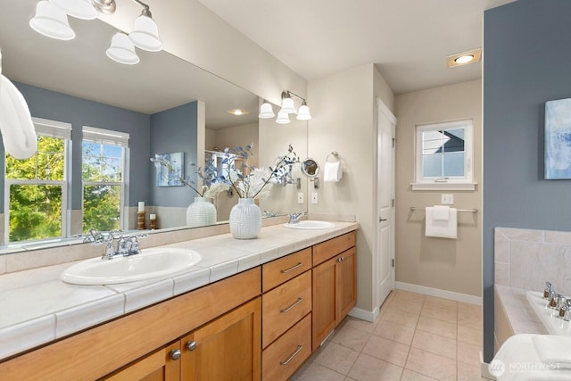 bathroom with a washtub, a sink, tile patterned flooring, double vanity, and baseboards