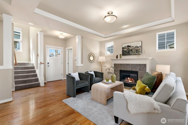 living room with light wood-style flooring, stairs, and a raised ceiling