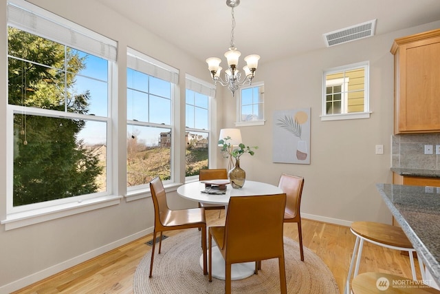 dining area with baseboards, visible vents, a chandelier, and light wood-type flooring