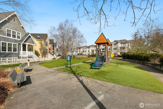 community jungle gym with a residential view, a lawn, and fence