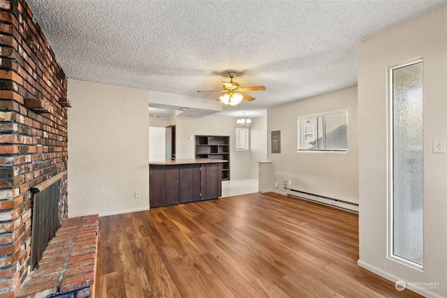 unfurnished living room with hardwood / wood-style floors, a baseboard heating unit, ceiling fan, a brick fireplace, and a textured ceiling