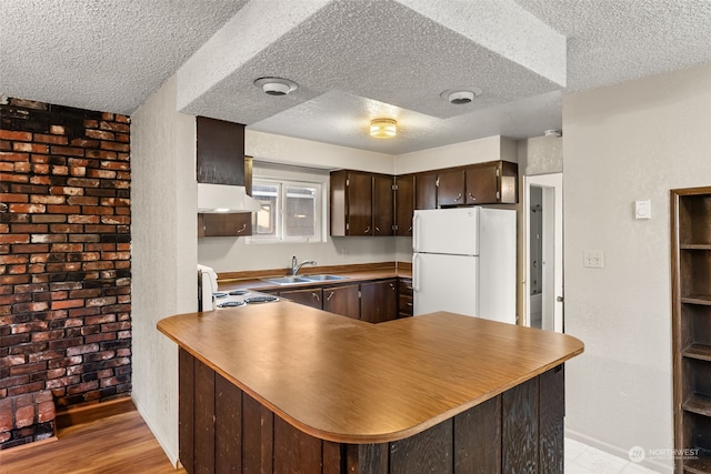 kitchen featuring sink, kitchen peninsula, custom range hood, white fridge, and electric stove