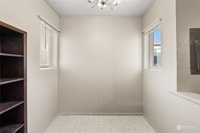 empty room featuring a notable chandelier and a textured ceiling