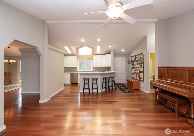 kitchen featuring arched walkways, a breakfast bar area, stainless steel dishwasher, white cabinets, and a kitchen island