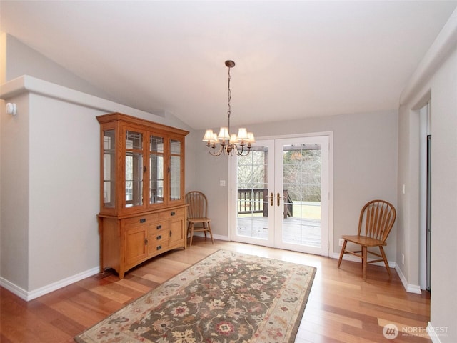 interior space with french doors, vaulted ceiling, a chandelier, light wood-type flooring, and baseboards