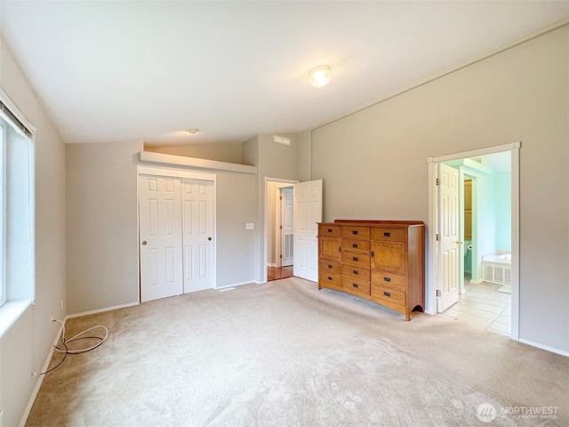 unfurnished bedroom with light carpet, connected bathroom, a closet, and lofted ceiling