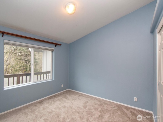 spare room with light carpet, vaulted ceiling, and baseboards