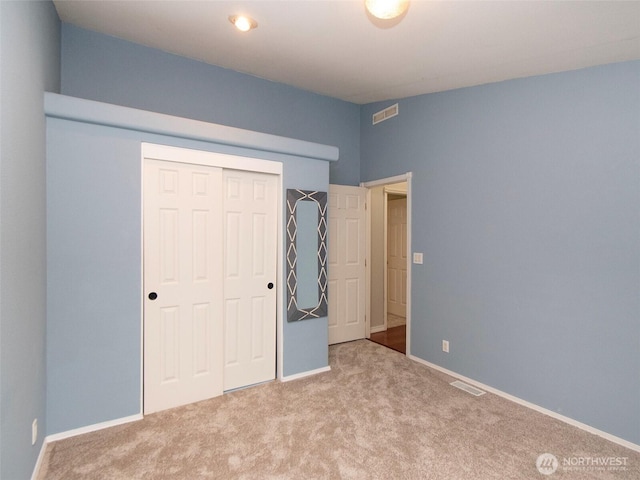 unfurnished bedroom featuring baseboards, visible vents, a closet, and light colored carpet