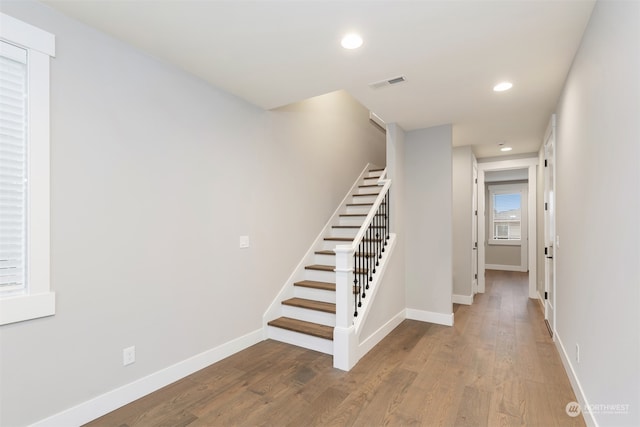 stairway featuring recessed lighting, wood finished floors, visible vents, and baseboards