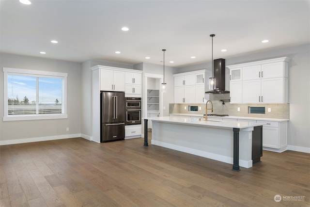 kitchen with white cabinetry, hanging light fixtures, high end refrigerator, and wall chimney exhaust hood