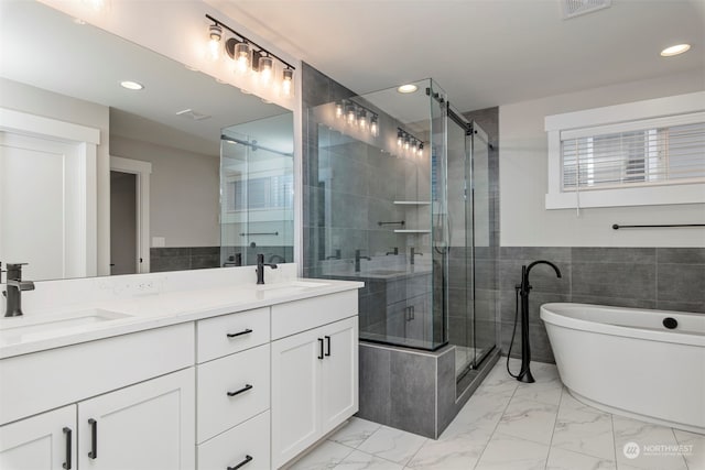 bathroom with vanity, independent shower and bath, and tile walls