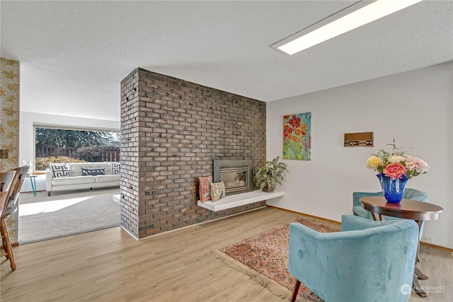 living area featuring wood-type flooring, a fireplace, and a textured ceiling