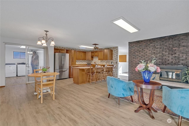 living room with light hardwood / wood-style flooring, a textured ceiling, washer and clothes dryer, and ceiling fan