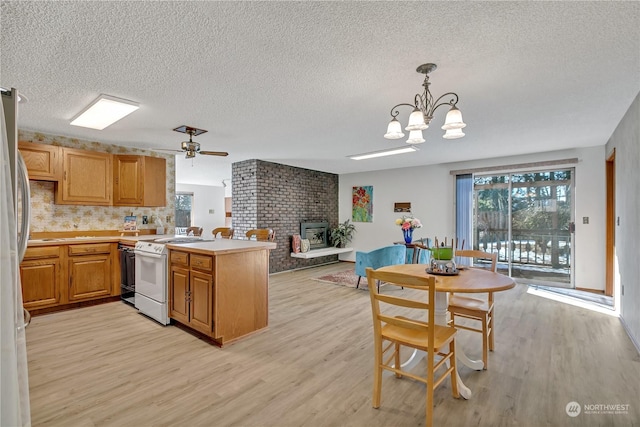 kitchen featuring hanging light fixtures, light hardwood / wood-style flooring, stainless steel fridge, kitchen peninsula, and electric stove