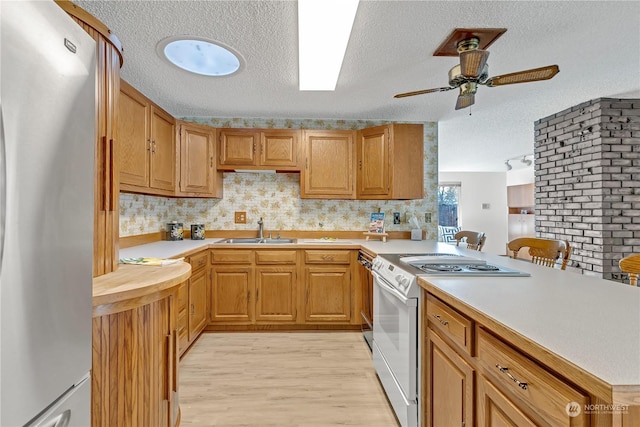 kitchen with white range with electric cooktop, sink, stainless steel fridge, light hardwood / wood-style floors, and kitchen peninsula