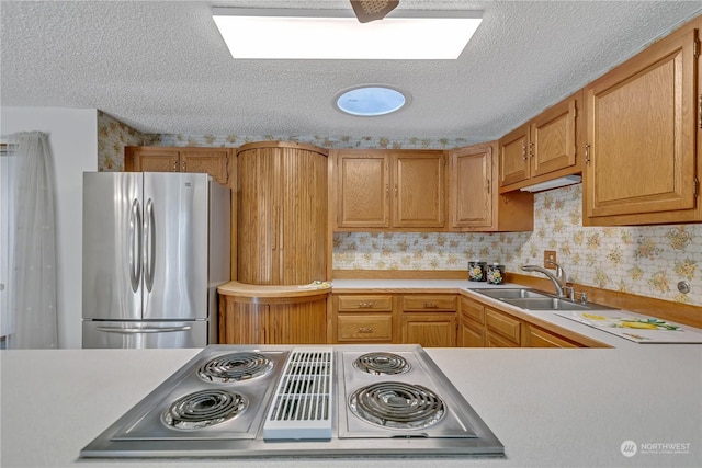 kitchen featuring electric stovetop, sink, a textured ceiling, and stainless steel refrigerator