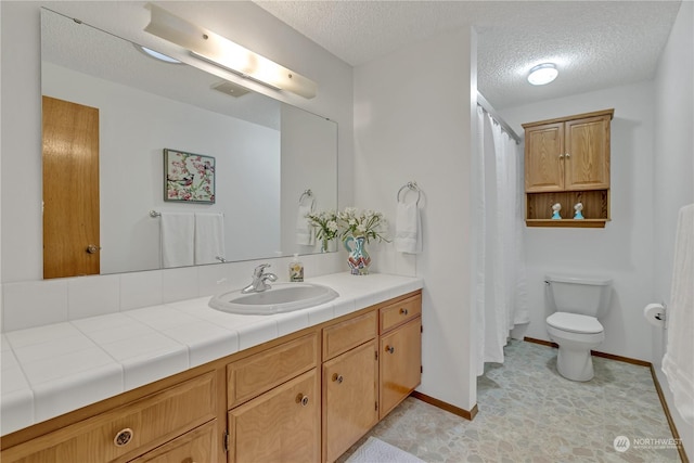 bathroom featuring vanity, toilet, and a textured ceiling