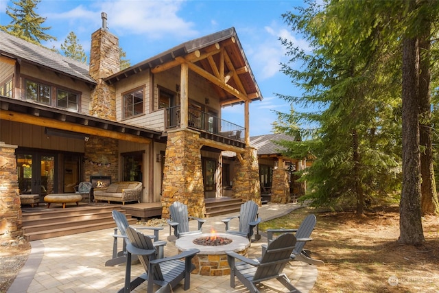 view of patio with a balcony, an outdoor stone fireplace, and a fire pit