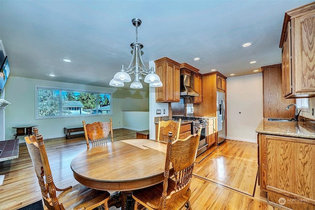 dining area with sink, a notable chandelier, and light hardwood / wood-style floors