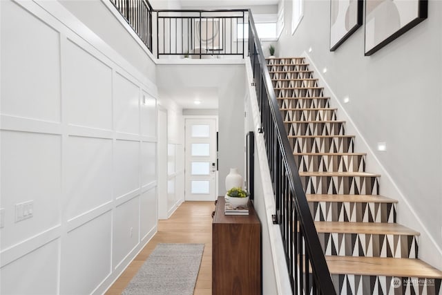 staircase featuring wood-type flooring and a towering ceiling