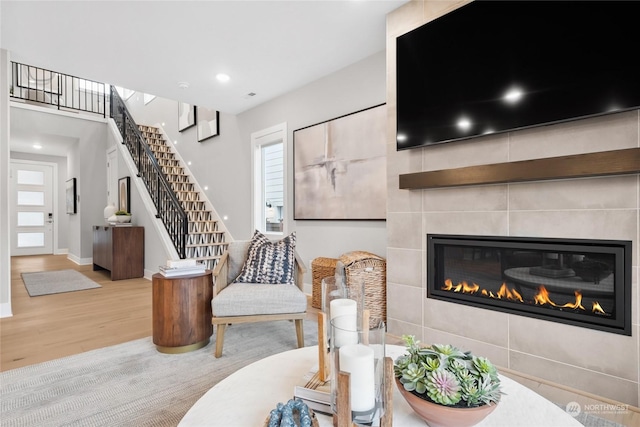 living room with a tiled fireplace and light wood-type flooring