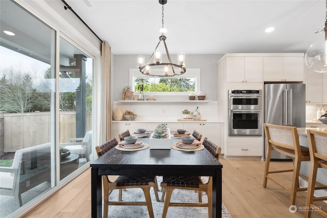 dining area with an inviting chandelier and light hardwood / wood-style flooring