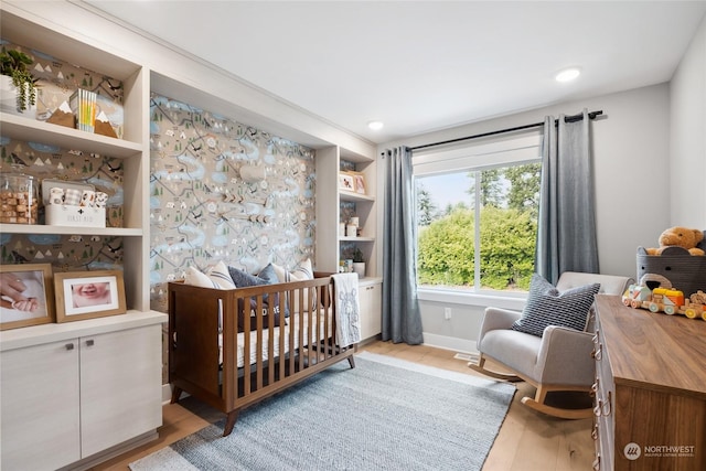 bedroom featuring a crib and light hardwood / wood-style flooring