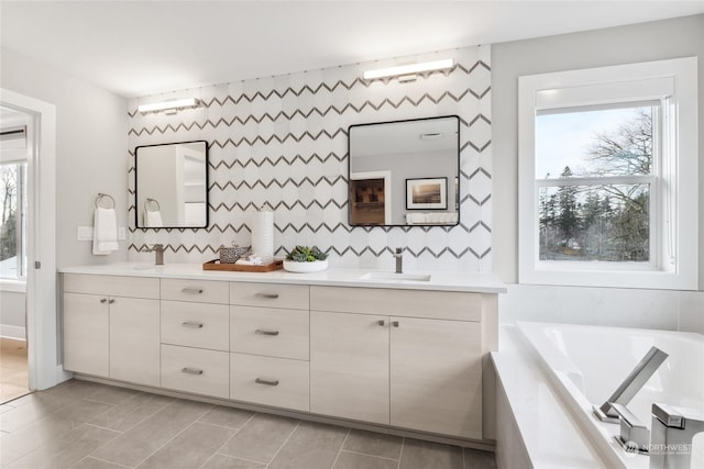 bathroom with vanity, a healthy amount of sunlight, a relaxing tiled tub, and tile patterned floors