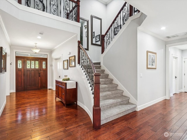 foyer entrance featuring baseboards, crown molding, visible vents, and dark wood-type flooring