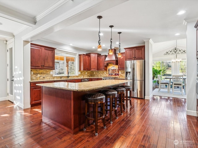 kitchen with plenty of natural light, stainless steel fridge with ice dispenser, a kitchen island, dark wood-type flooring, and custom exhaust hood