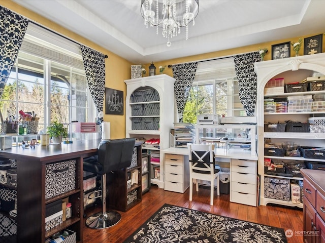 home office with a notable chandelier, a raised ceiling, and hardwood / wood-style floors