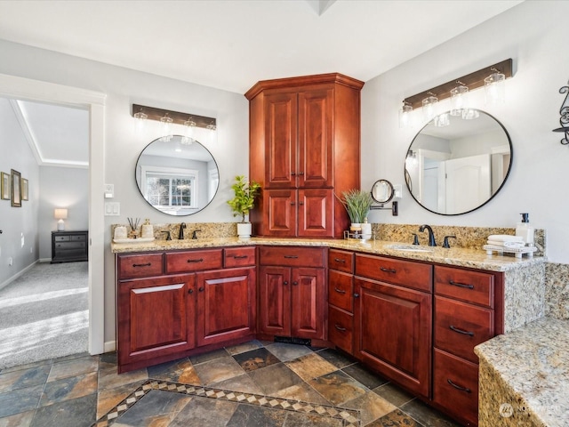 bathroom with double vanity, a sink, stone tile flooring, and baseboards