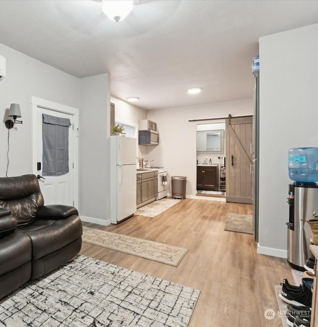 living room featuring light wood-style floors, baseboards, and a barn door