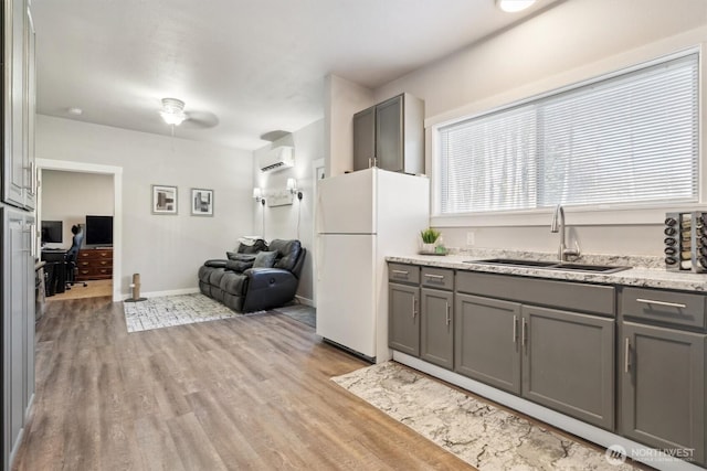 kitchen featuring freestanding refrigerator, a sink, and gray cabinetry