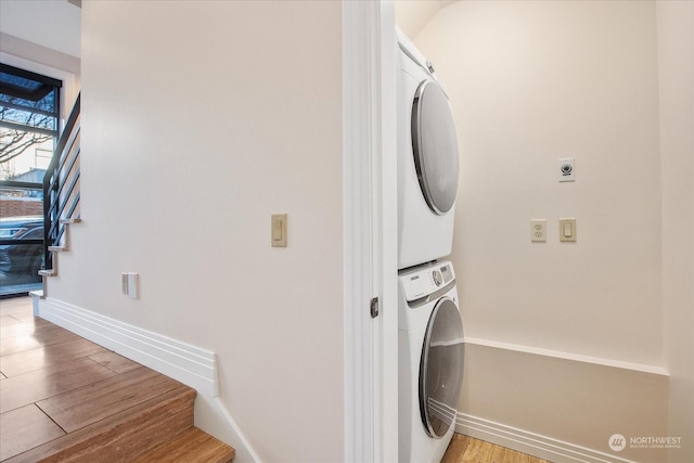 laundry area with stacked washer and dryer and light hardwood / wood-style flooring