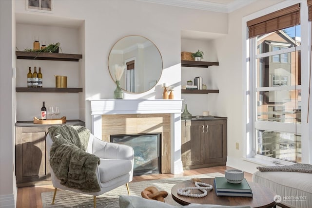 sitting room featuring a tile fireplace, ornamental molding, and light hardwood / wood-style floors