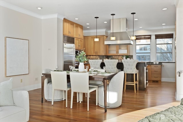 dining space featuring ornamental molding, sink, and hardwood / wood-style floors