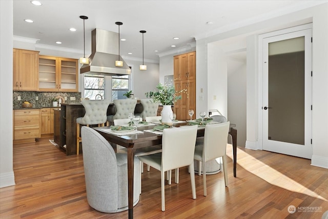 dining space with crown molding and light wood-type flooring