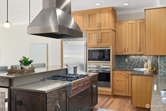 kitchen with crown molding, island range hood, built in appliances, and decorative light fixtures