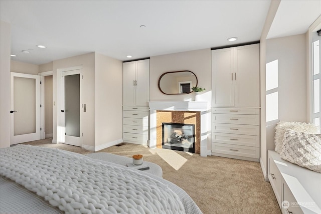 bedroom with a tiled fireplace and light colored carpet