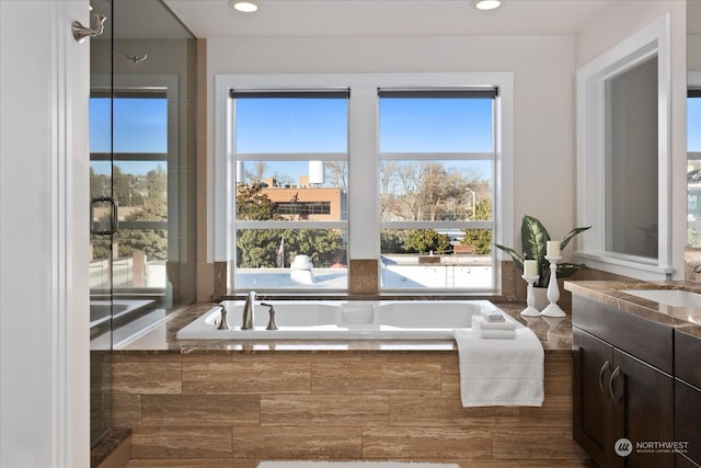 bathroom featuring vanity and tiled bath